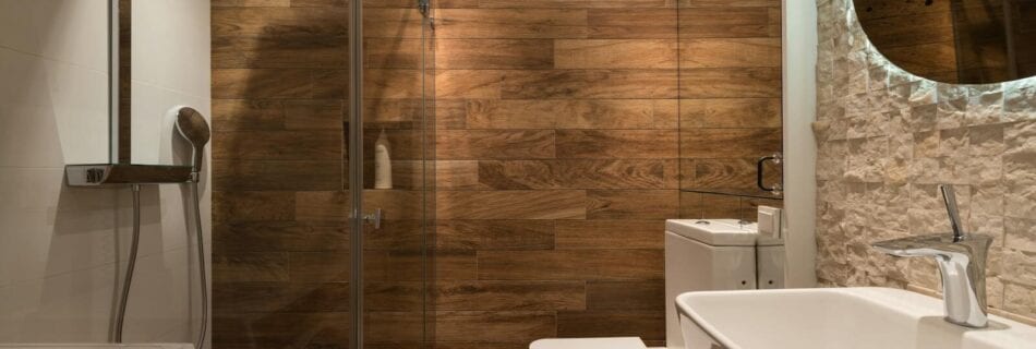 stylish modern bathroom interior design with glass shower enclosure toilet bowl and sink under oval mirror